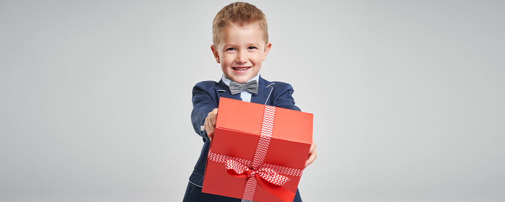 Bambino vestito elegante tiene in mano un regalo
